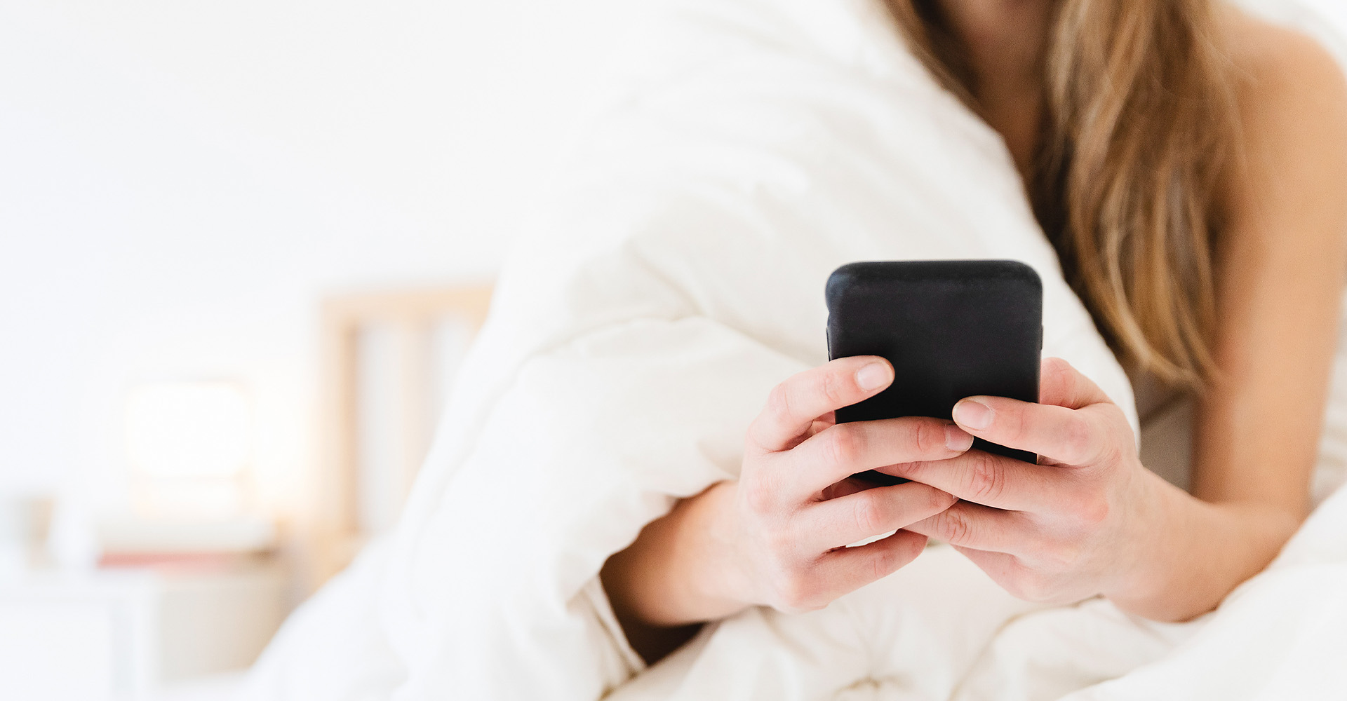 Frau sucht Im Bett auf dem Handy nach Informationen